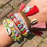 Dana Levy personalised name bracelet that reads luv you lots with friendship bracelets on a wrist at Glastonbury.