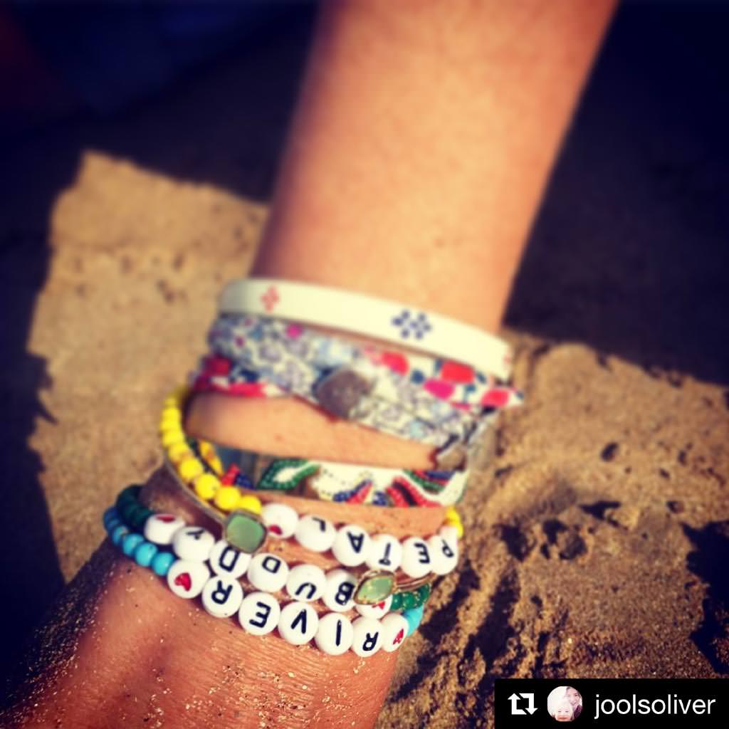 Jools Oliver wearing Dana Levy's personalised name glass bead bracelets with her children's names on them, on the sand. 