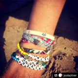 Jools Oliver wearing Dana Levy's personalised name glass bead bracelets with her children's names on them, on the sand. 