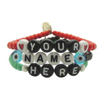 Dana Levy personalised name glass bead bracelet spelling out "Your Name Here" in different bead colours in a stack on a white background. 