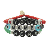 Dana Levy personalised name glass bead bracelet spelling out "Your Name Here" in different bead colours in a stack on a white background. 